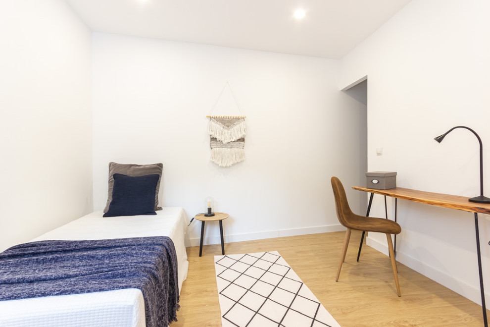 Cette photo montre une petite chambre d'amis blanche et bois industrielle avec un mur blanc, un sol en bois brun et un sol marron.