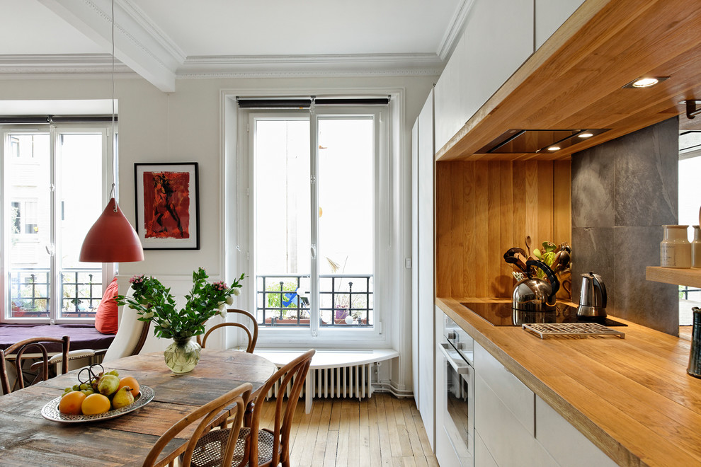 This is an example of a mid-sized contemporary single-wall open plan kitchen in Paris with wood benchtops, medium hardwood floors, a single-bowl sink, beaded inset cabinets, beige cabinets, beige splashback, timber splashback, stainless steel appliances and multiple islands.