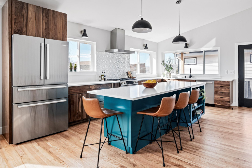 This is an example of a mid-sized midcentury l-shaped eat-in kitchen in Denver with an undermount sink, flat-panel cabinets, turquoise cabinets, granite benchtops, white splashback, porcelain splashback, stainless steel appliances, medium hardwood floors, with island, brown floor, white benchtop and vaulted.