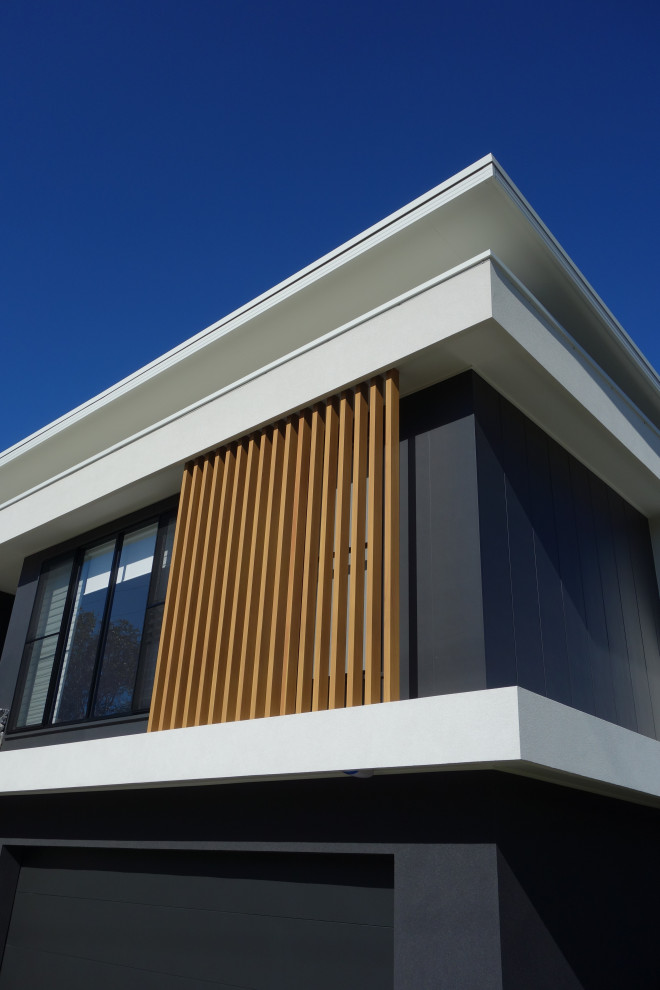 Design ideas for a large modern two-storey black house exterior in Wollongong with a flat roof and a metal roof.