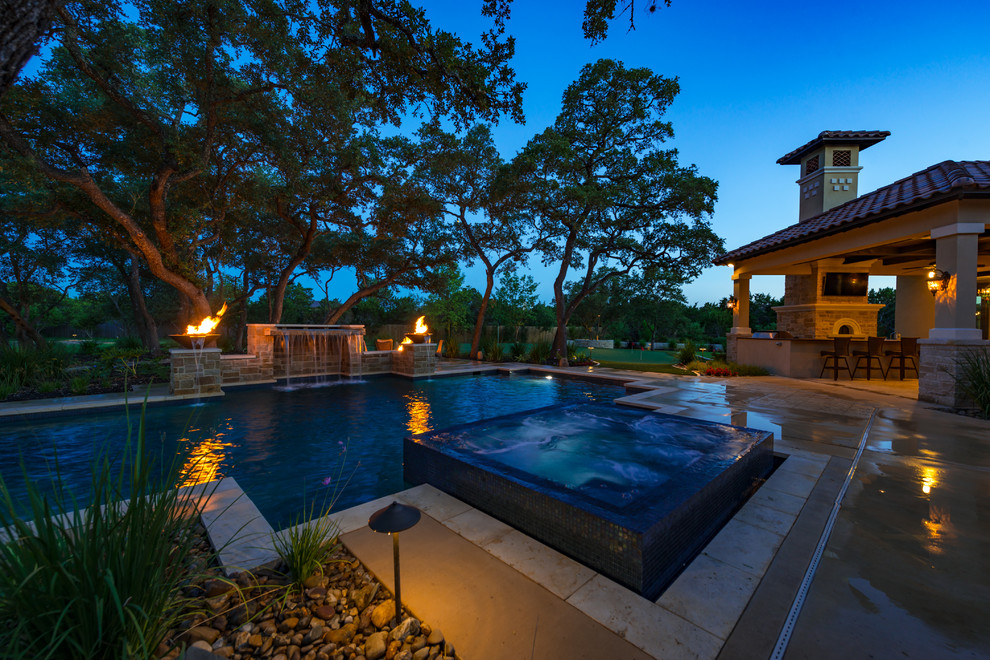 Large mediterranean backyard custom-shaped pool in Austin with a hot tub and concrete pavers.