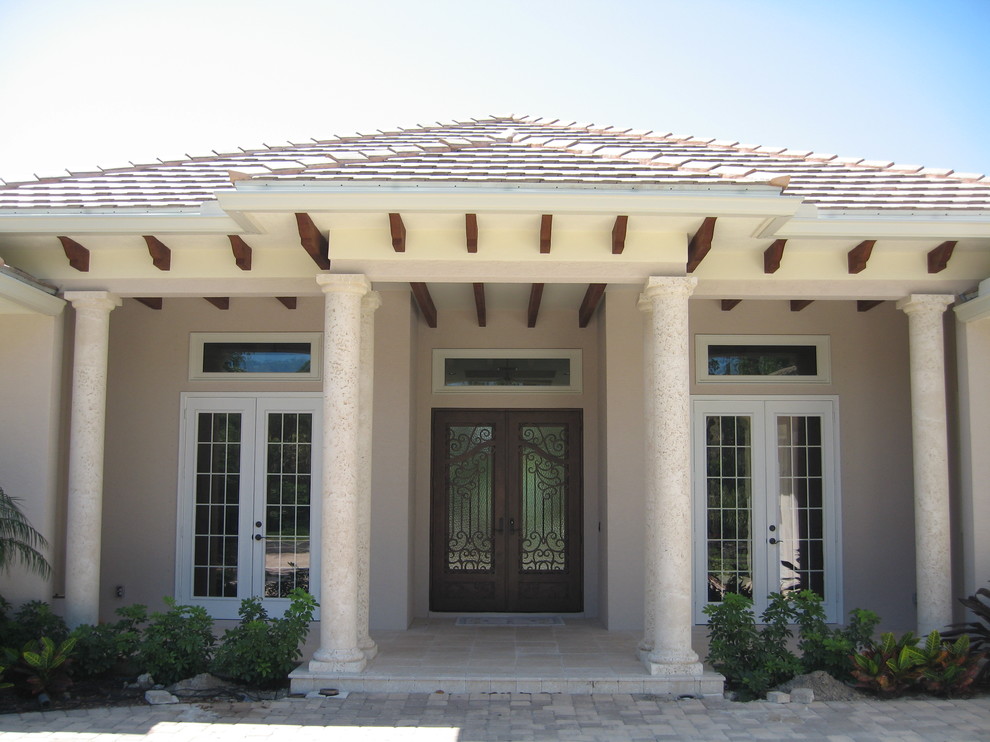 Example of a large tuscan beige one-story stucco exterior home design in Miami with a tile roof