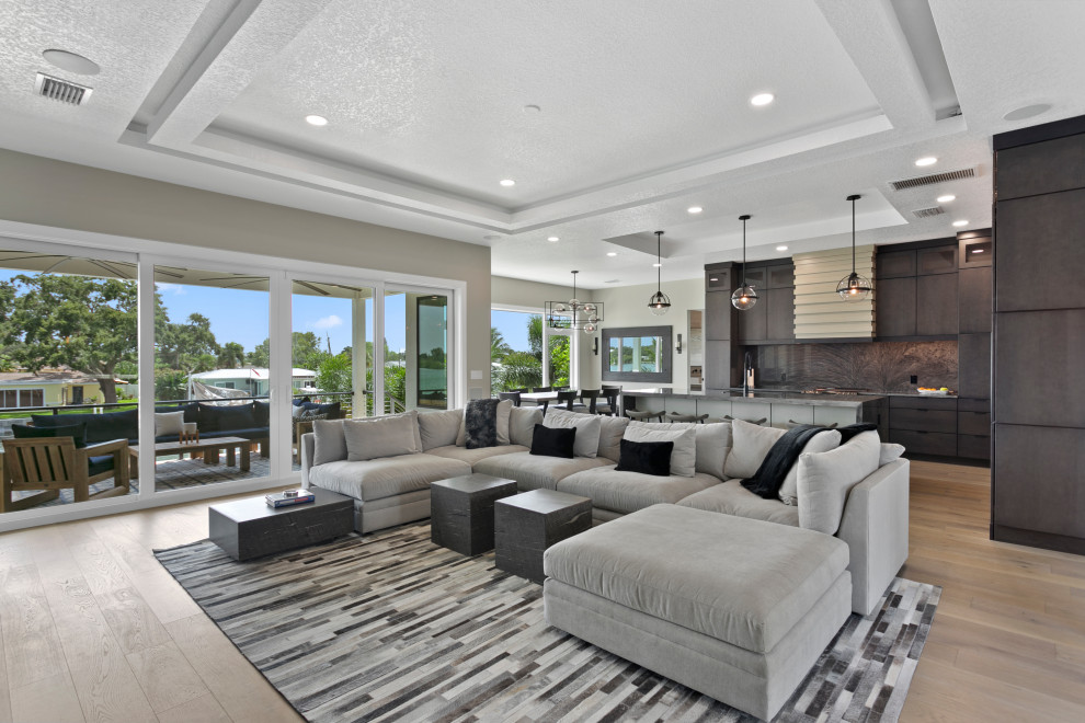 Example of a mid-sized trendy loft-style light wood floor and gray floor family room design in Tampa with gray walls, a ribbon fireplace, a stone fireplace and a media wall