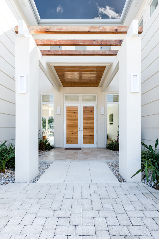 Mid-sized tropical front door in Other with a double front door, a light wood front door and white walls.
