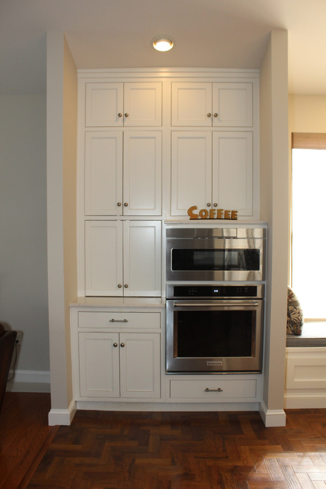 Bild på ett mellanstort vintage vit vitt kök, med en rustik diskho, luckor med profilerade fronter, vita skåp, bänkskiva i kvarts, vitt stänkskydd, rostfria vitvaror, mörkt trägolv, en köksö och brunt golv
