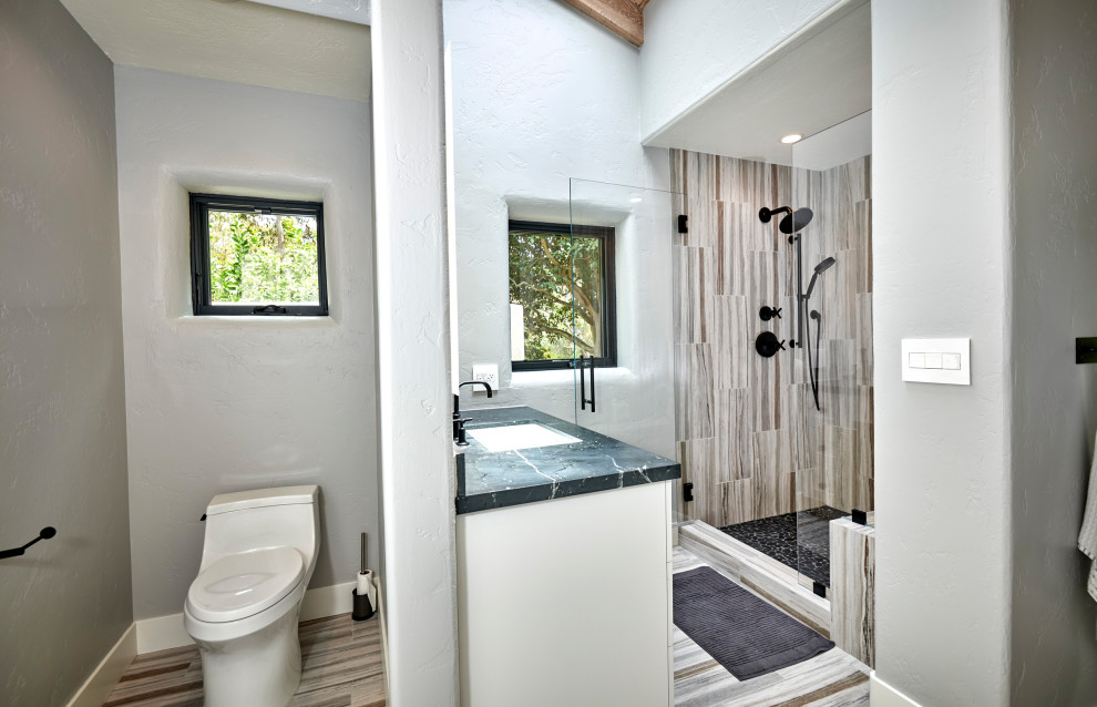 Inspiration for a large classic ensuite bathroom in Denver with recessed-panel cabinets, white cabinets, a freestanding bath, a walk-in shower, a two-piece toilet, black tiles, ceramic tiles, white walls, mosaic tile flooring, a submerged sink, quartz worktops, white floors, an open shower, black worktops, a shower bench, a single sink, a built in vanity unit and a wood ceiling.