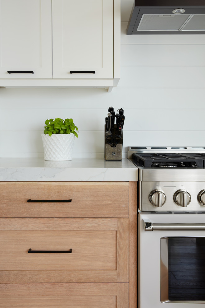 Bild på ett mellanstort funkis vit vitt kök, med en undermonterad diskho, skåp i shakerstil, vita skåp, bänkskiva i kvarts, vitt stänkskydd, rostfria vitvaror, ljust trägolv, en köksö och beiget golv