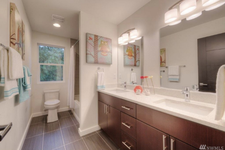 Photo of a mid-sized contemporary kids bathroom in Seattle with an undermount sink, flat-panel cabinets, medium wood cabinets, engineered quartz benchtops, an alcove tub, a shower/bathtub combo, a one-piece toilet, white walls and porcelain floors.