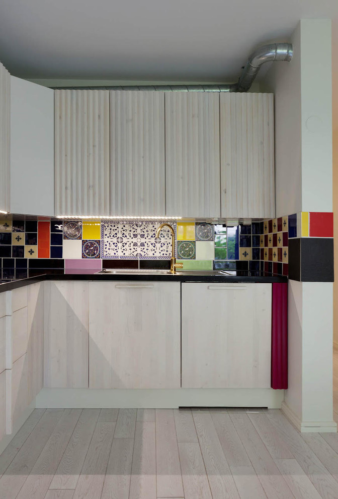 Inspiration for a small eclectic single-wall kitchen in Stockholm with multi-coloured splashback, cement tile splashback, light hardwood floors, grey floor and black benchtop.
