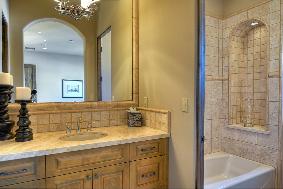 This is an example of a mid-sized traditional bathroom in Phoenix with an undermount sink, medium wood cabinets, a shower/bathtub combo, a one-piece toilet, beige tile and beige walls.