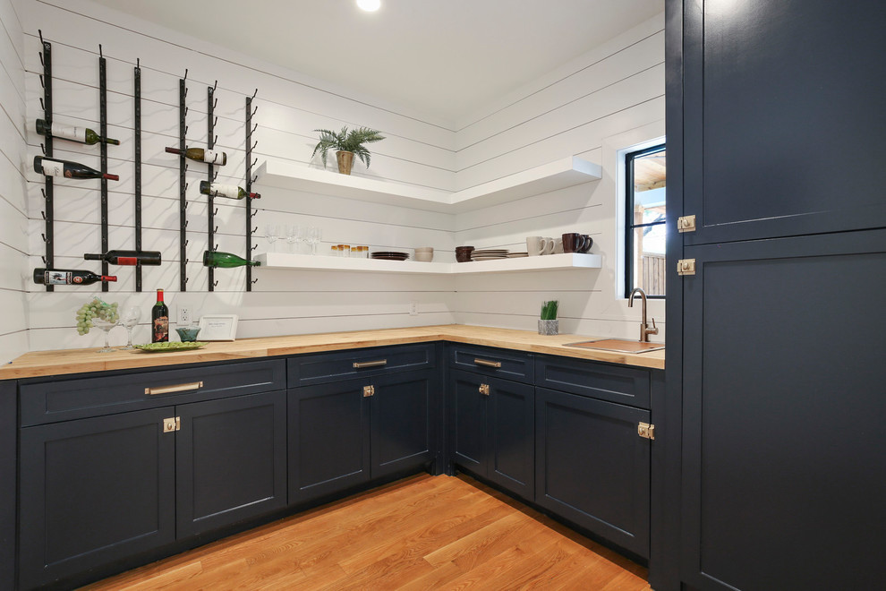 Design ideas for a scandinavian kitchen pantry in Dallas with an undermount sink, shaker cabinets, blue cabinets, wood benchtops, white splashback, timber splashback, stainless steel appliances and light hardwood floors.