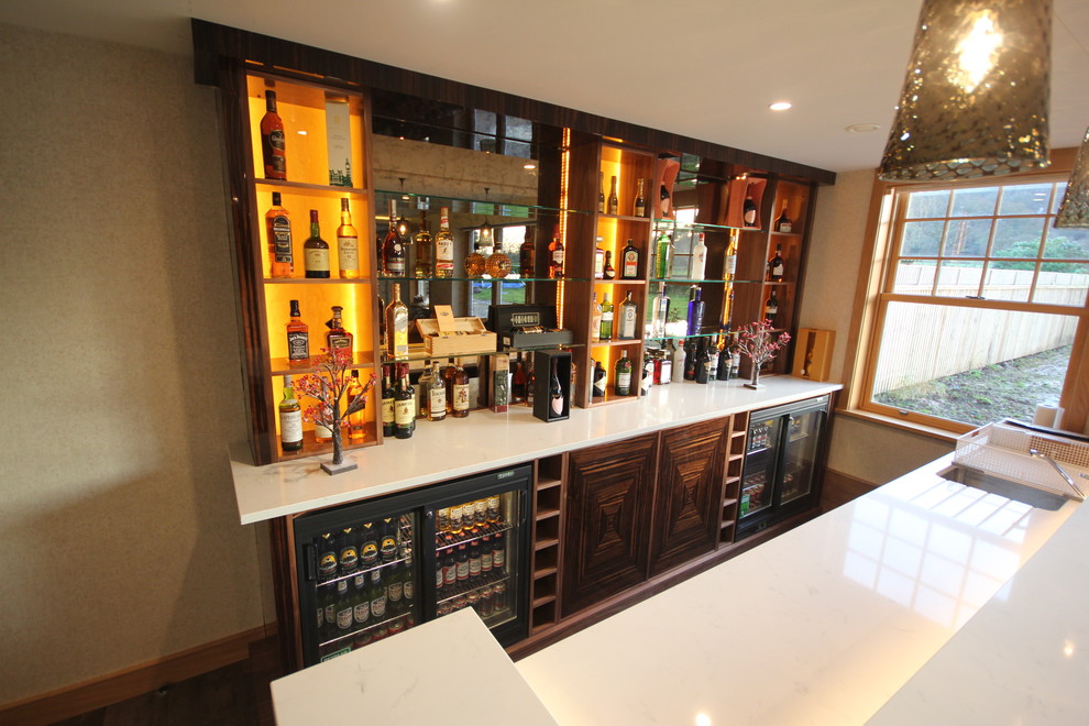 Design ideas for a large modern l-shaped wet bar in Cheshire with an undermount sink, flat-panel cabinets, dark wood cabinets, quartz benchtops, painted wood floors and mirror splashback.