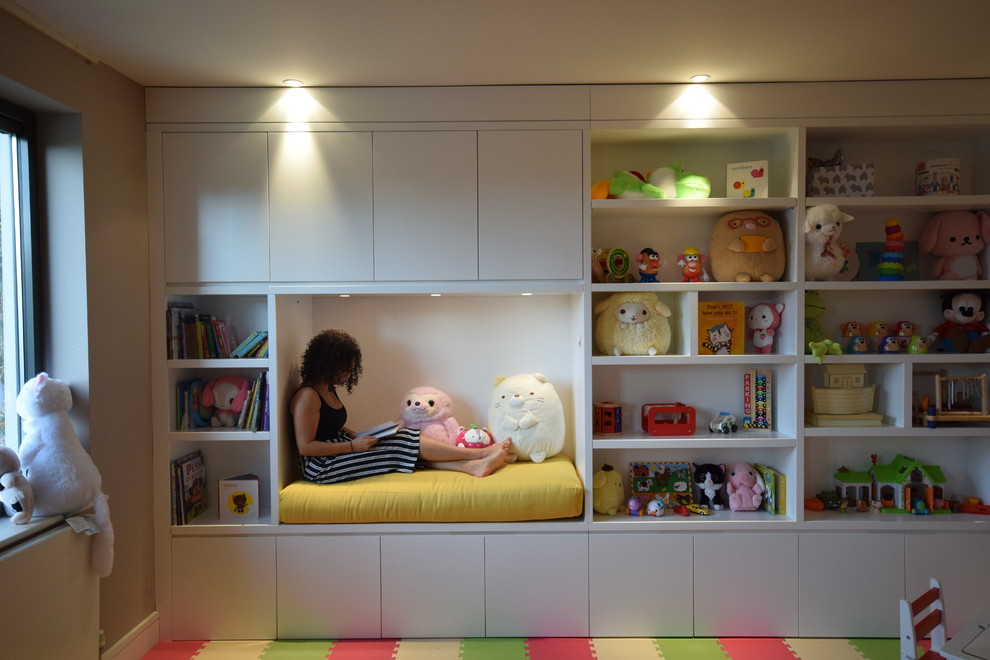 This is an example of a large contemporary gender-neutral kids' playroom for kids 4-10 years old in London with beige walls.