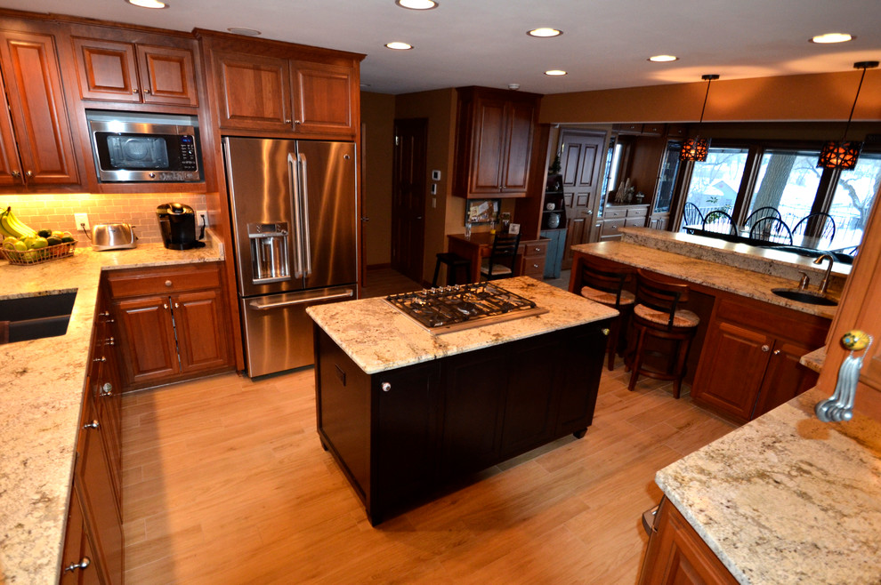 Eat-in kitchen - transitional l-shaped medium tone wood floor eat-in kitchen idea in Milwaukee with a double-bowl sink, beaded inset cabinets, medium tone wood cabinets, granite countertops, stone slab backsplash, stainless steel appliances and an island
