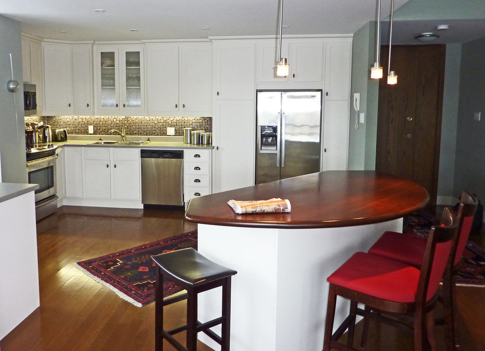 Mid-sized transitional l-shaped medium tone wood floor and brown floor open concept kitchen photo with a drop-in sink, shaker cabinets, white cabinets, quartz countertops, multicolored backsplash, mosaic tile backsplash, stainless steel appliances, an island and gray countertops