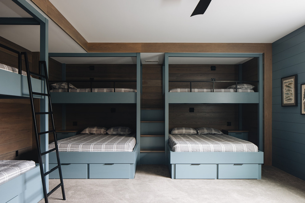 Boys' Bunk Room - Boys' room featuring custom blue built-in bunk beds that sleep eight, blue shiplap walls, black metal ladder, dark wood accents, and gray carpet.