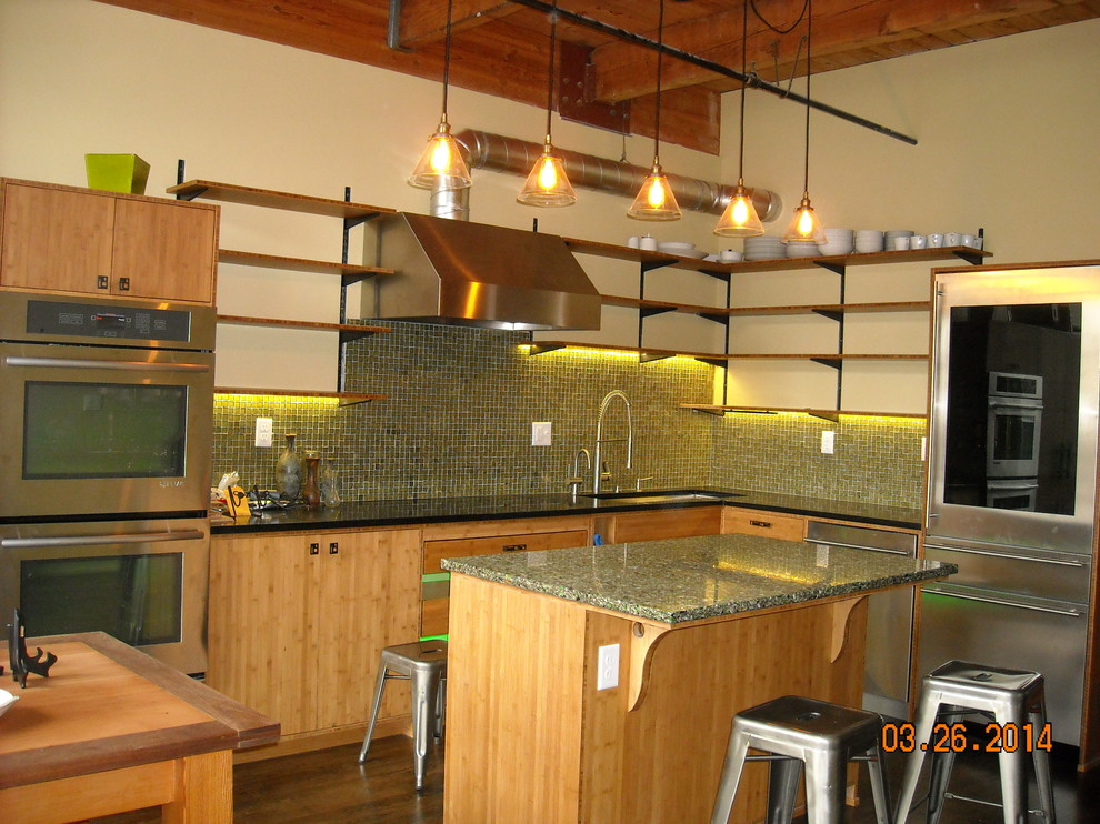 Photo of an industrial eat-in kitchen in Portland with an undermount sink, flat-panel cabinets, light wood cabinets, recycled glass benchtops, green splashback, glass sheet splashback, stainless steel appliances, dark hardwood floors and with island.