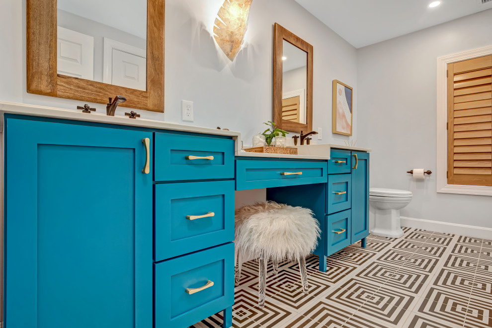 Medium sized eclectic family bathroom in Boston with flat-panel cabinets, blue cabinets, an alcove bath, a shower/bath combination, a two-piece toilet, grey walls, porcelain flooring, a submerged sink, engineered stone worktops, multi-coloured floors, a shower curtain, white worktops, double sinks and a built in vanity unit.