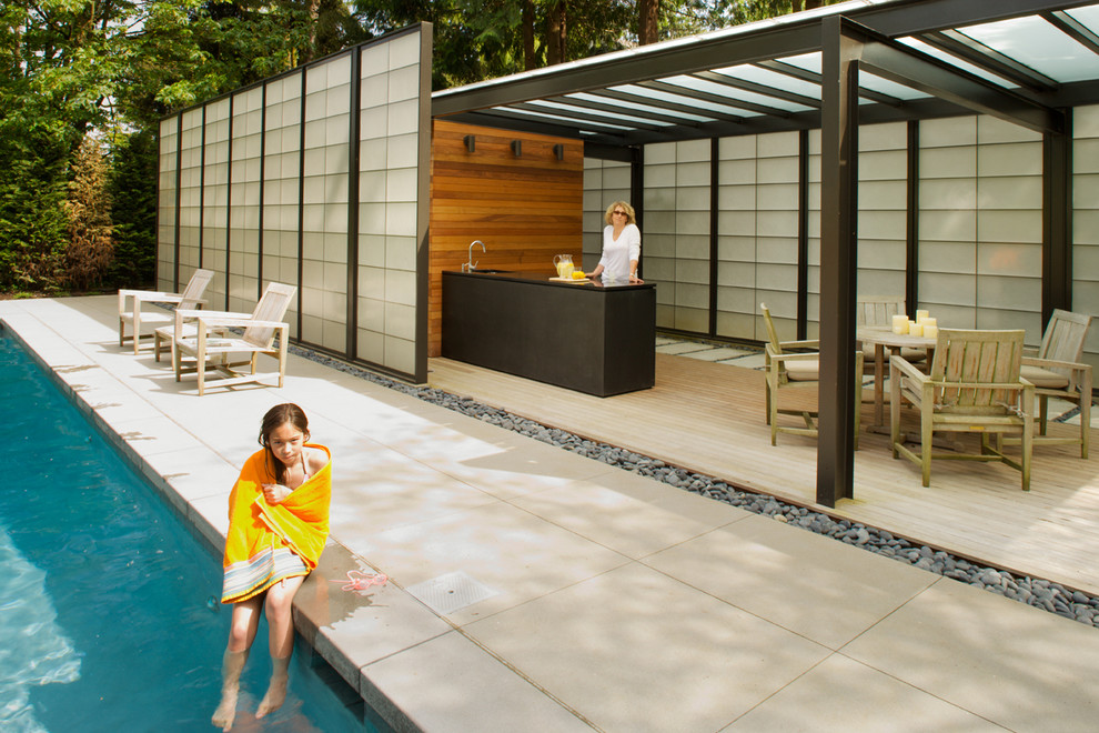 Design ideas for a large contemporary backyard rectangular pool in Seattle with a pool house and natural stone pavers.
