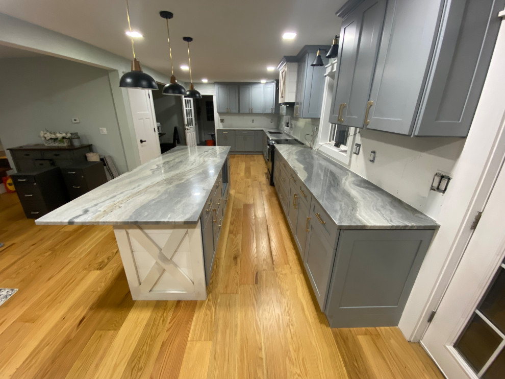 Photo of a large farmhouse l-shaped kitchen/diner in Bridgeport with a double-bowl sink, shaker cabinets, blue cabinets, granite worktops, stainless steel appliances, medium hardwood flooring, an island, brown floors and blue worktops.
