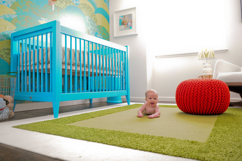 Small modern nursery in Orange County with multi-coloured walls and medium hardwood floors for boys.