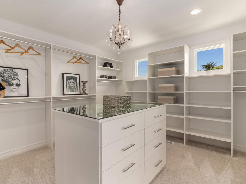 Design ideas for a large gender-neutral walk-in wardrobe in Chicago with flat-panel cabinets, white cabinets, carpet and beige floor.