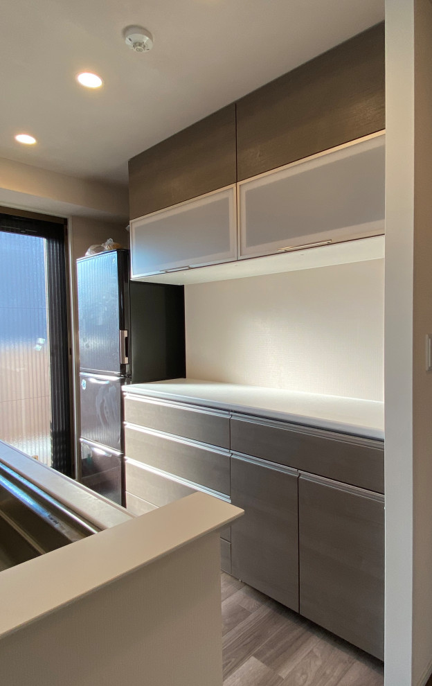 Ejemplo de cocina lineal abierta con puertas de armario de madera oscura, suelo de contrachapado, suelo beige, encimeras blancas y papel pintado