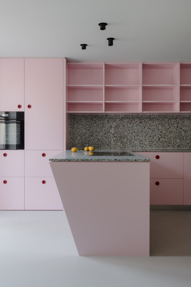 Пример оригинального дизайна: огромная угловая кухня в современном стиле с врезной мойкой, плоскими фасадами, розовыми фасадами, столешницей терраццо, серым фартуком, черной техникой, полуостровом, серым полом и серой столешницей