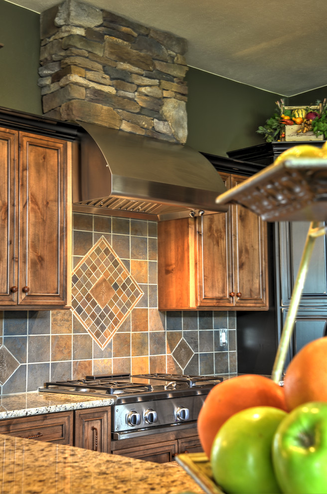 Inspiration for a large rustic l-shaped open concept kitchen remodel in Seattle with a double-bowl sink, raised-panel cabinets, medium tone wood cabinets, granite countertops, multicolored backsplash, travertine backsplash, stainless steel appliances and an island