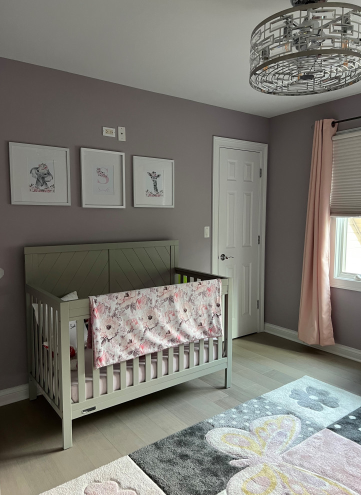 Exemple d'une grande chambre de bébé fille chic avec un mur violet et parquet clair.