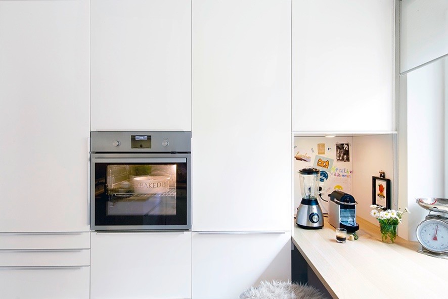 Imagen de cocina actual pequeña con armarios con paneles lisos, puertas de armario blancas y encimera de madera