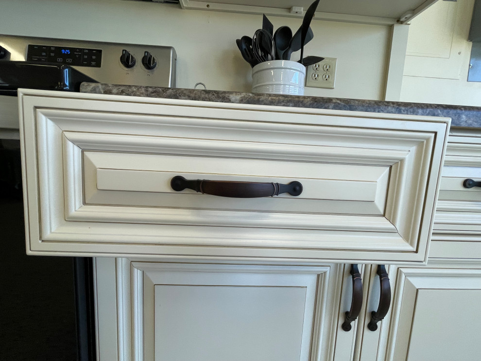 Modelo de cocina cerrada con armarios con paneles con relieve, puertas de armario blancas y encimera de laminado