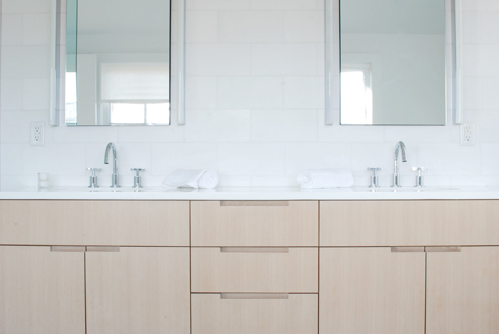 Photo of a contemporary bathroom in New York with furniture-like cabinets, light wood cabinets, engineered quartz benchtops, white tile and stone tile.