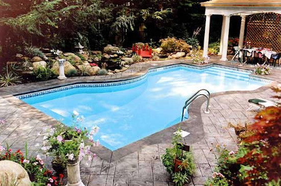Backyard stone and custom-shaped pool photo