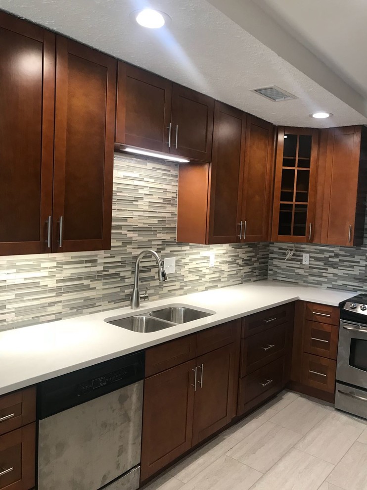 Example of a mid-sized transitional u-shaped porcelain tile and gray floor enclosed kitchen design in Houston with an undermount sink, shaker cabinets, medium tone wood cabinets, quartz countertops, multicolored backsplash, glass tile backsplash, stainless steel appliances, no island and white countertops