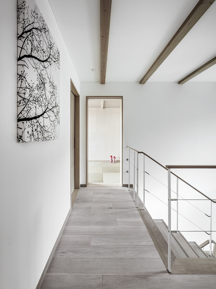 This is an example of a modern hallway in Osaka with white walls, painted wood floors and grey floor.