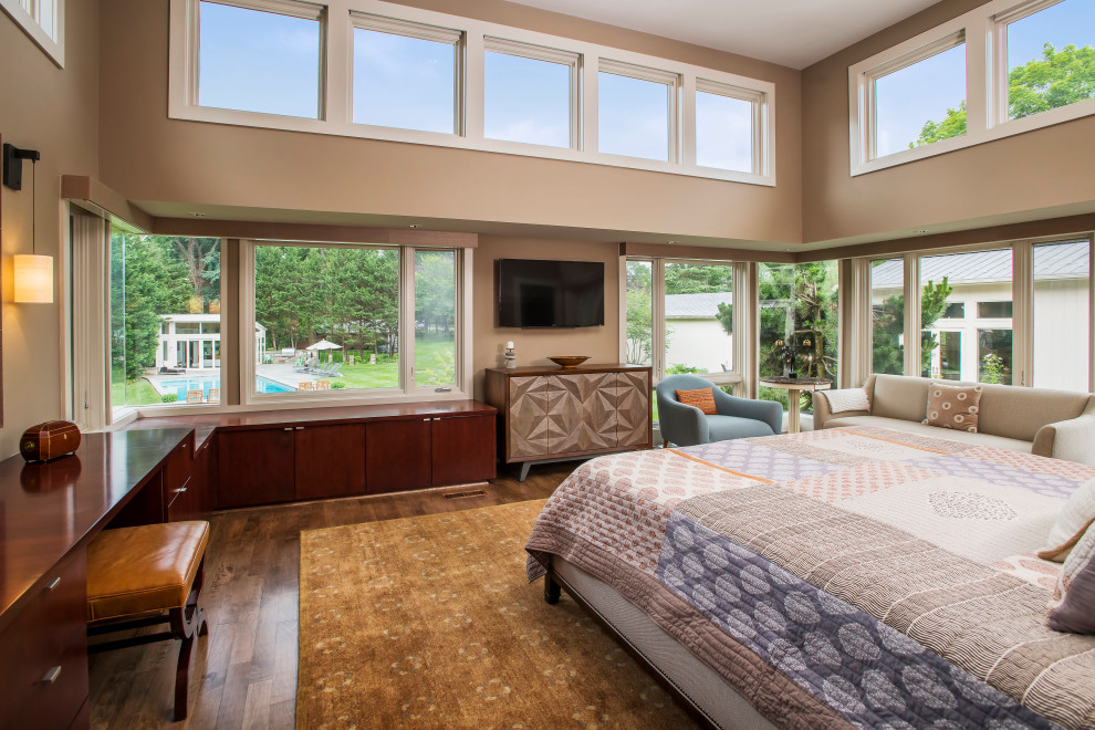 Foto de dormitorio principal, televisión y blanco contemporáneo con paredes beige, suelo de madera en tonos medios y suelo marrón