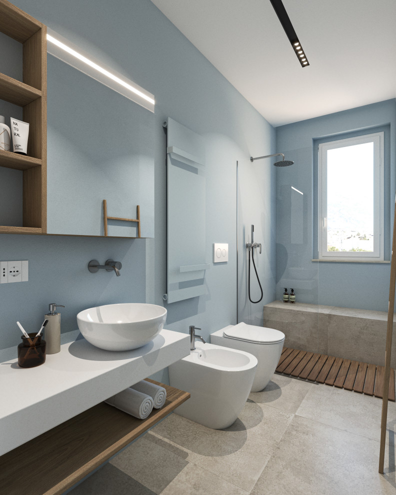 Modern inredning av ett stort vit vitt badrum med dusch, med öppna hyllor, skåp i ljust trä, en kantlös dusch, en toalettstol med separat cisternkåpa, beige kakel, porslinskakel, blå väggar, klinkergolv i porslin, ett fristående handfat, laminatbänkskiva, beiget golv och med dusch som är öppen