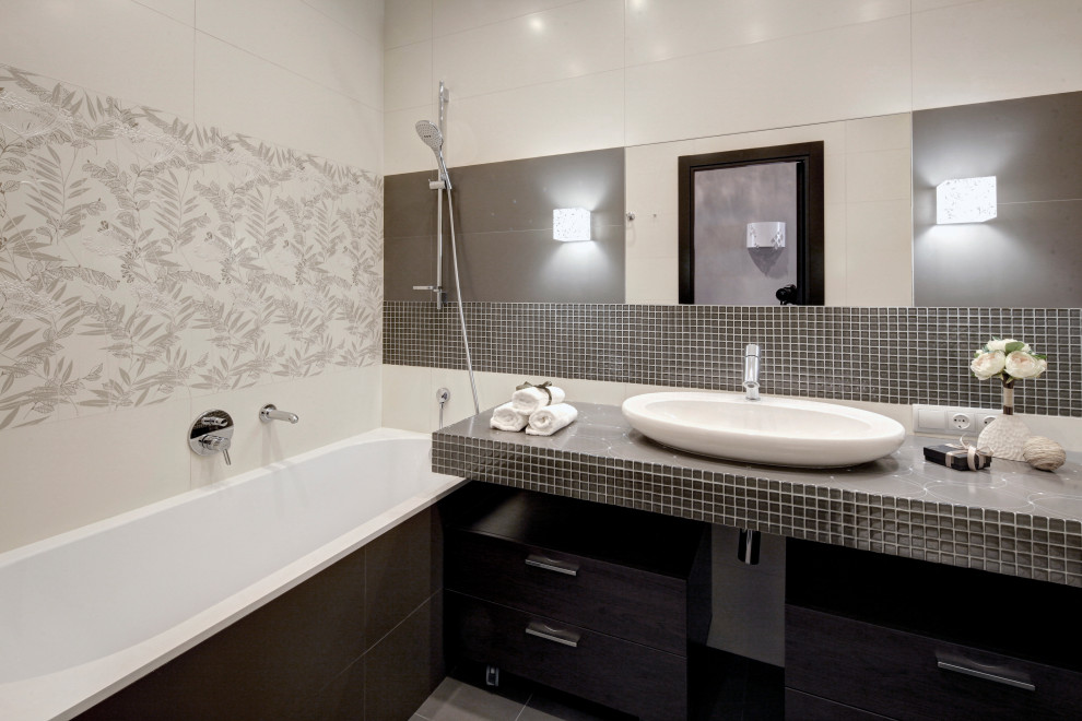 Inspiration for a medium sized traditional grey and white ensuite bathroom in Moscow with flat-panel cabinets, dark wood cabinets, a submerged bath, a wall mounted toilet, beige tiles, mosaic tiles, beige walls, porcelain flooring, a built-in sink, tiled worktops, grey floors, grey worktops, a single sink, a floating vanity unit, a drop ceiling and panelled walls.