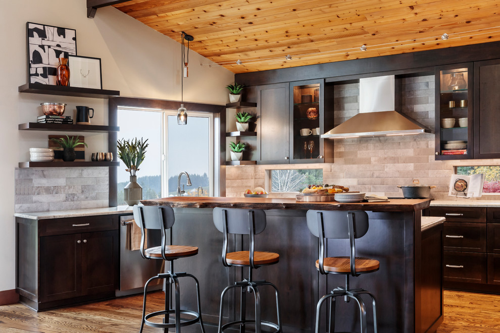 Transitional l-shaped kitchen in Portland with shaker cabinets, black cabinets, grey splashback, stainless steel appliances, medium hardwood floors, with island, brown floor and white benchtop.