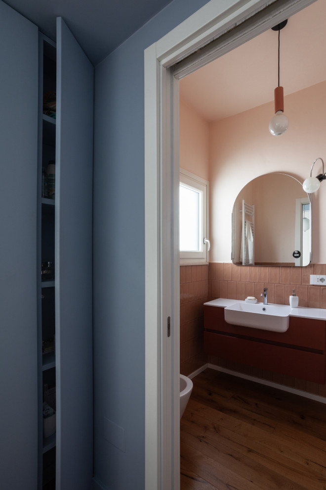 Foto di un bagno di servizio contemporaneo con ante lisce, WC a due pezzi, piastrelle rosa, piastrelle in ceramica, pareti rosa, parquet scuro, lavabo integrato e mobile bagno sospeso