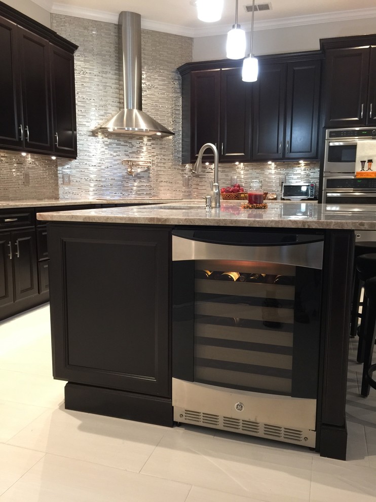 This is an example of a mid-sized transitional l-shaped eat-in kitchen in Orlando with a double-bowl sink, shaker cabinets, black cabinets, metallic splashback, glass sheet splashback, stainless steel appliances, porcelain floors and with island.