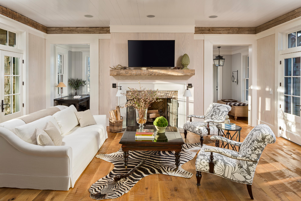 Design ideas for a country enclosed family room in Other with beige walls, medium hardwood floors, a standard fireplace and a wall-mounted tv.