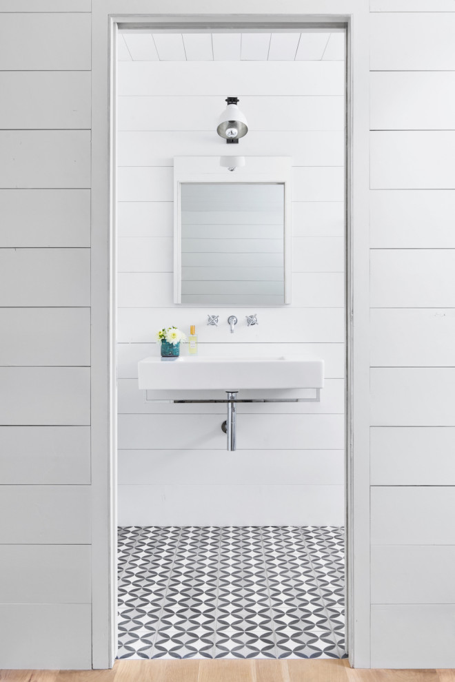 Photo of a small country powder room in Austin with white cabinets, white walls, ceramic floors, a wall-mount sink, black floor, white benchtops, a floating vanity, wood and panelled walls.