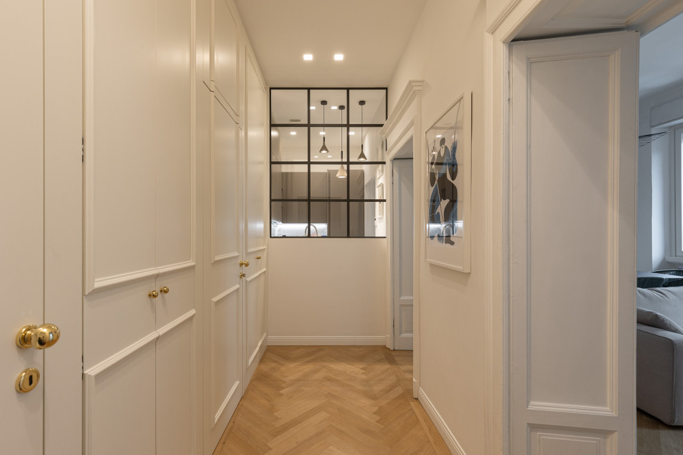 Idee per un ingresso minimal con pareti bianche, parquet chiaro e armadio