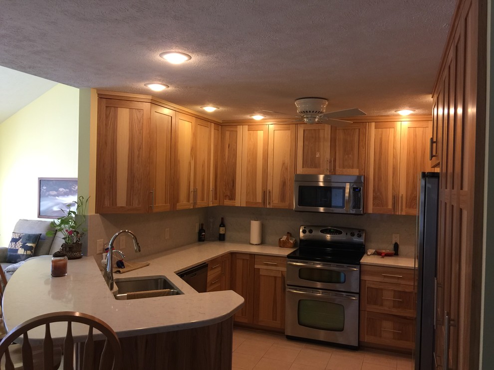 Inspiration for a small transitional u-shaped porcelain tile and beige floor eat-in kitchen remodel in Omaha with an undermount sink, shaker cabinets, medium tone wood cabinets, quartz countertops, white backsplash, stainless steel appliances, a peninsula and white countertops