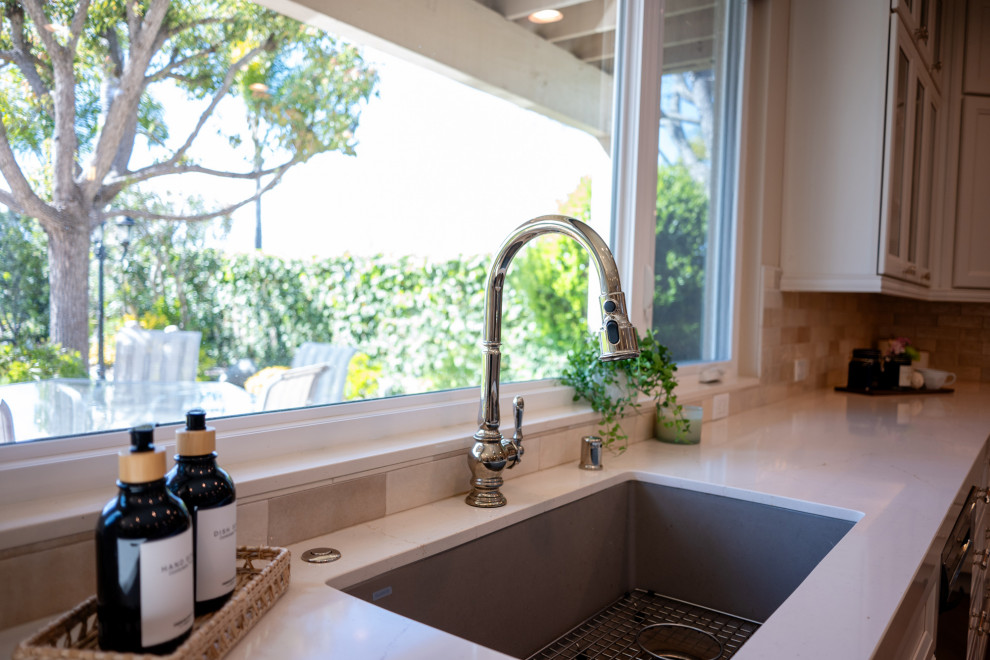 Large transitional l-shaped vinyl floor and brown floor open concept kitchen photo in San Diego with an undermount sink, shaker cabinets, white cabinets, quartz countertops, beige backsplash, porcelain backsplash, stainless steel appliances, an island and white countertops
