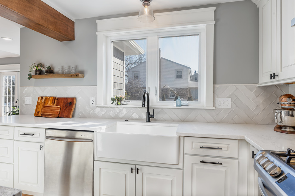 Inspiration for a mid-sized transitional l-shaped eat-in kitchen in Boston with a farmhouse sink, raised-panel cabinets, white cabinets, quartz benchtops, white splashback, subway tile splashback, stainless steel appliances, light hardwood floors, with island, beige floor and white benchtop.