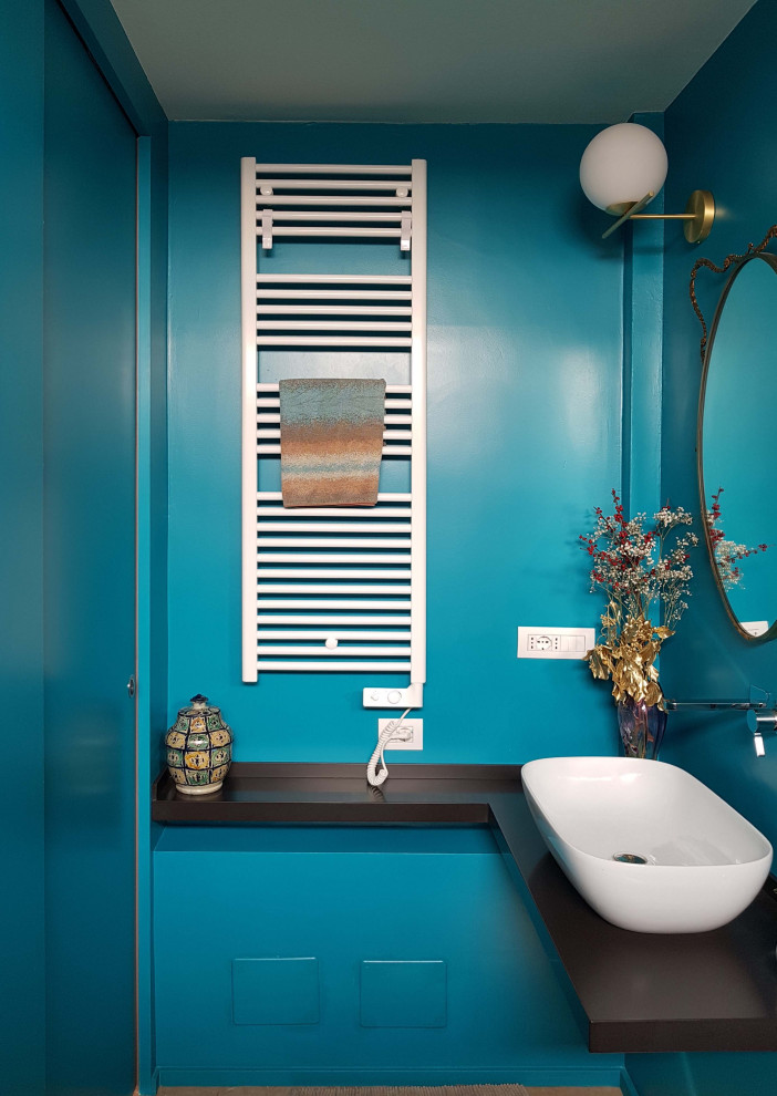 Foto på ett litet funkis brun toalett, med öppna hyllor, en vägghängd toalettstol, ett fristående handfat, bänkskiva i akrylsten, flerfärgad kakel, porslinskakel, blå väggar och marmorgolv