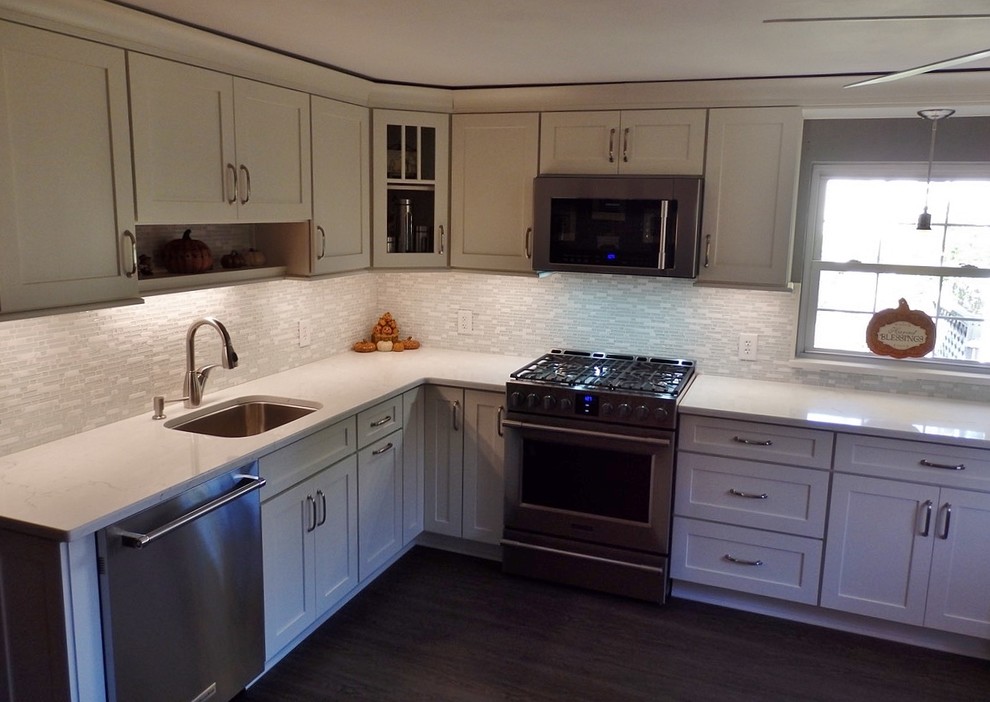 Design ideas for a mid-sized transitional l-shaped eat-in kitchen in Philadelphia with an undermount sink, shaker cabinets, white cabinets, quartz benchtops, white splashback, mosaic tile splashback, stainless steel appliances, dark hardwood floors and no island.